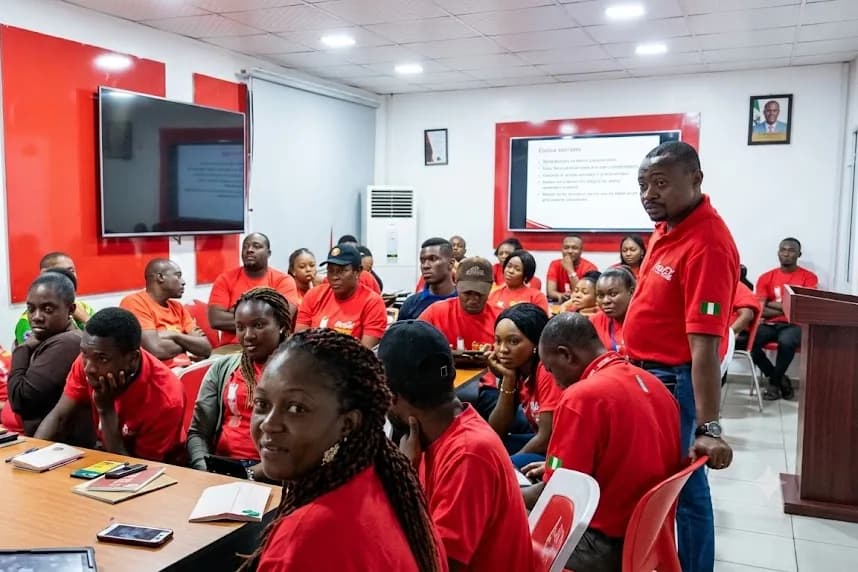 Uniformed staff seated through a training session in a branded conference room